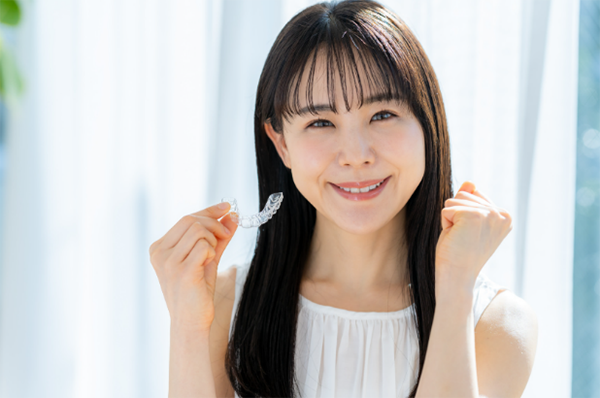 マウスピース型矯正装置を持つ女性